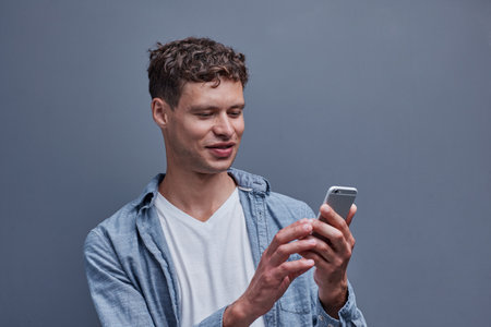 a man on a gray background holds a phone in his hand