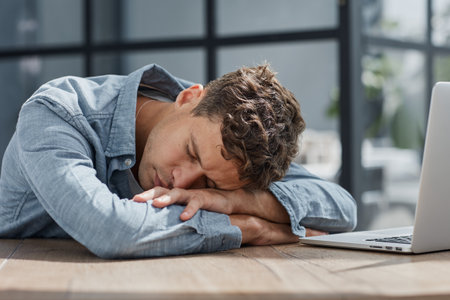 young office man at a laptop sleeping at his workplace