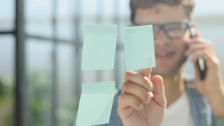 business man standing in front of stickers glass wall and write task on sticker at his office place