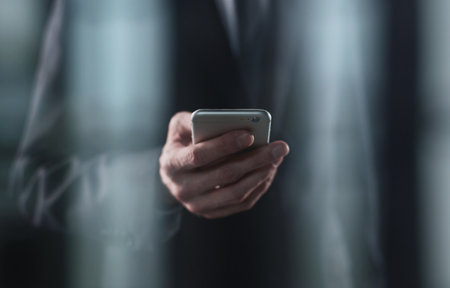 businessman looking at smartphone screen in hand on dark backgroundの写真素材