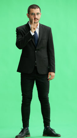 young man in full growth. isolated on green background pointing with fingerの写真素材