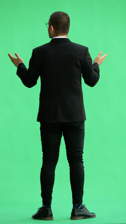 young man in full growth. isolated on green background demonstrates with handsの写真素材