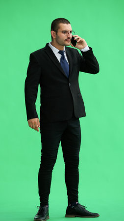 man in full growth. isolated on green background using phoneの写真素材
