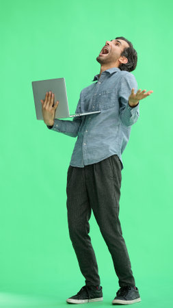 young man in full growth. isolated on green background using laptop