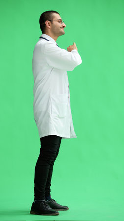 male doctor in a white coat on a green background smiling in full lengthの写真素材