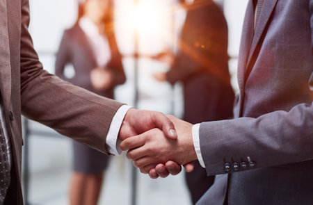close-up of a handshake of business partners against the background of colleaguesの写真素材