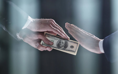 A mans hand in a black suit holds out a wad of money, which refuses. World Anti-Corruption Day...