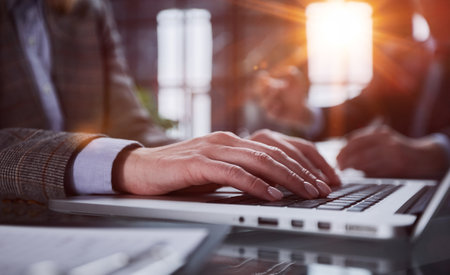 mans hands typing on laptop keyboard in interiorの写真素材