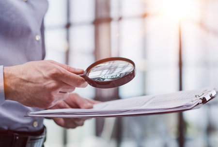 Businessman looking through a magnifying glass to documentsの写真素材