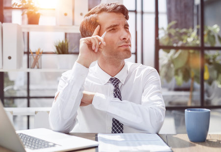 Image of successful businessman 30s thinking and holding index finger at foreheadの写真素材