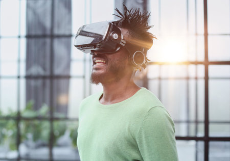 Cool handsome african american man put on virtual reality goggles for the first time in the office.の写真素材