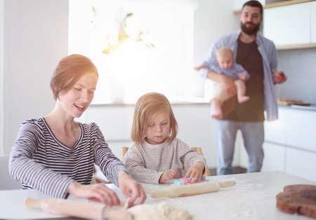 Young parents playing with children in the kitchenの写真素材