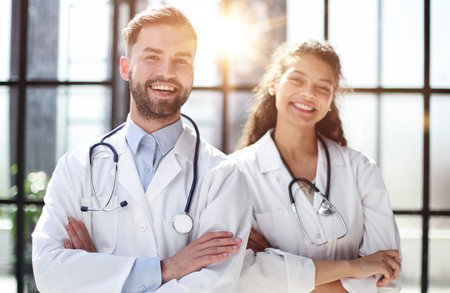 a female doctor and a male doctor are standing in the office with their arms crossedの写真素材