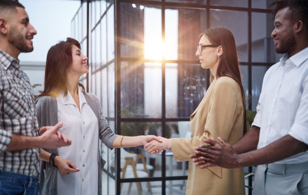 Two professional business people shaking hands in an office lobbyの写真素材