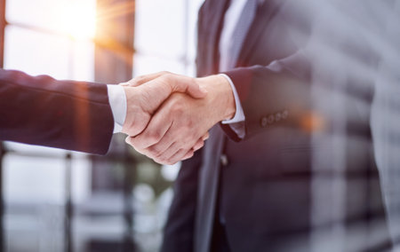 executives shaking hands in front of their manager and a colleagueの写真素材