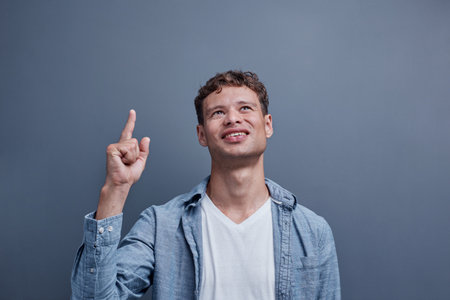 a man on a gray background points to the topの写真素材