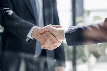 executives shaking hands in front of their manager and a colleagueの写真素材