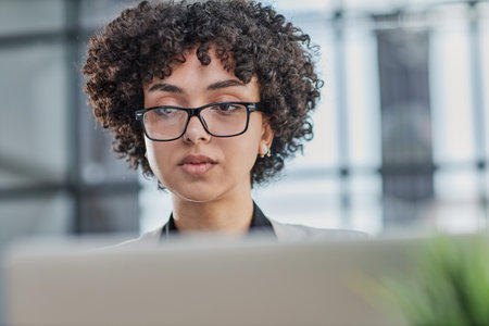 Portrait of Young Successful Caucasian Businesswoman Sitting at Desk Working on Laptopの写真素材