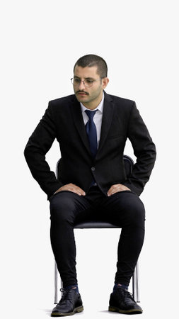 young man in full growth. isolated on a white background sitting on a chairの写真素材