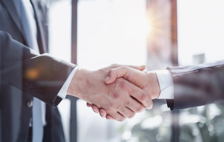 executives shaking hands in front of their manager and a colleague
