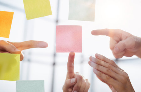 Hand pointing at pink paper or post against office background