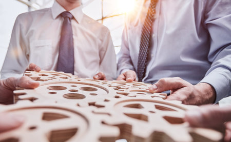 Business people holding wooden gears in officeの写真素材