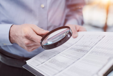 Businessman looking through a magnifying glass to documentsの写真素材