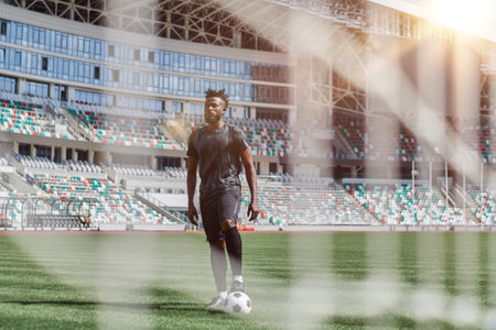 Young african american man holding soccer ball against soccer goal netの写真素材