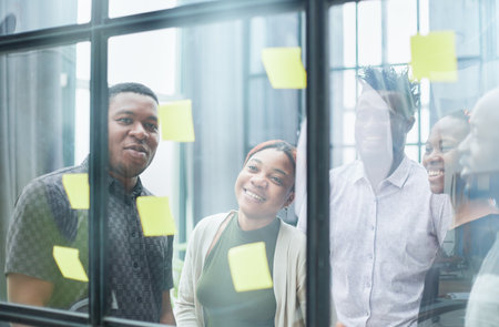 a team of young designers sticking notes on glass in a modern officeの写真素材