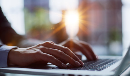 Close-up of male hands using laptop at officeの写真素材