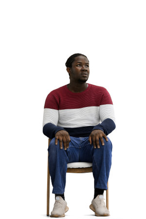 A man in a multi-colored jacket with a backpack on a White background sits on a chairの写真素材
