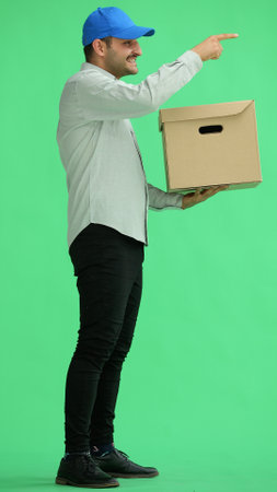 full-length male courier holding a box on a green backgroundの写真素材