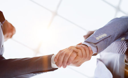 Business partners shaking hands in meeting hall bottom view