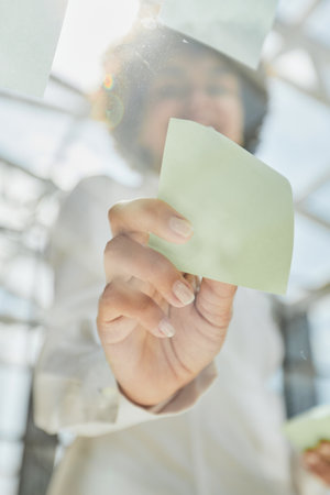 woman working on project plan using sticky papers notes on glass