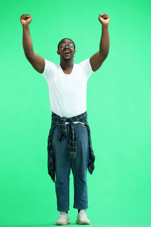 A man with a shirt tied at his waist on a green background waves his handsの写真素材