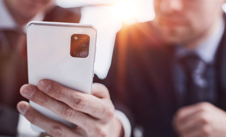 Businessman typing success on touch screen phone at AI generated workplaceの写真素材