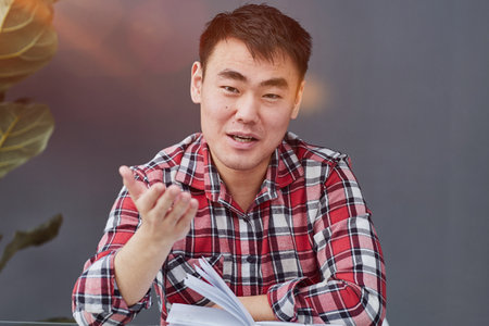 Young Asian man sitting at the table with his chin proppedの写真素材