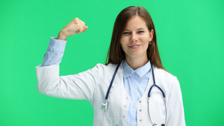 Female doctor, close-up, on a green background, shows strengthの写真素材