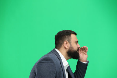 A man, close-up, on a green background, tells a secretの写真素材
