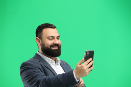 Man, close-up, on a green background, with a phoneの写真素材