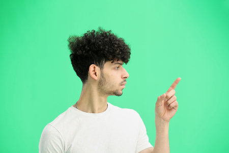 A man, on a green background, in close-up, points to the sideの写真素材