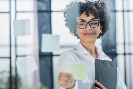 woman working on project plan using sticky papers notes on glass