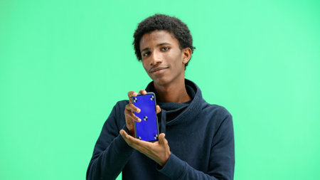 A man, close-up, on a green background, shows a phoneの写真素材