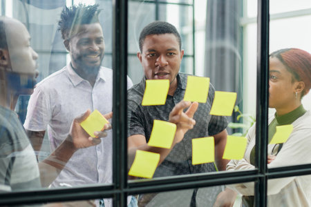 a team of young designers sticking notes on glass in a modern office
