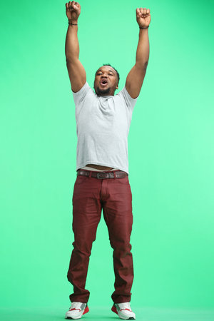 Man, full-length, on a green background, raised their hands up