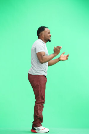 A man, full-length, on a green background, clapping