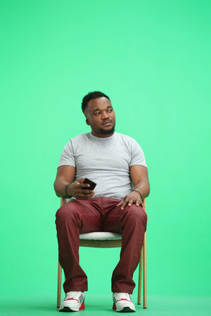 Man, on a green background, sitting on a chair