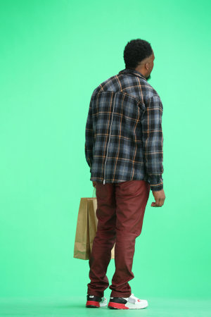 A man, full-length, on a green background, with bagsの写真素材