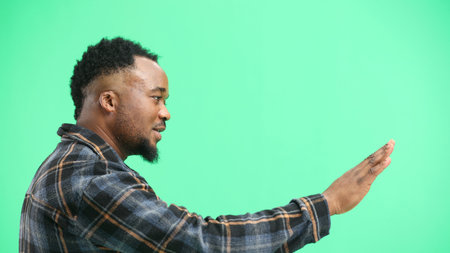A man, close-up, on a green background, shows a stop signの写真素材