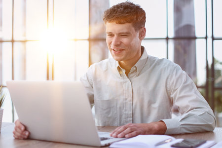 young man sitting in the office working at a laptopの写真素材